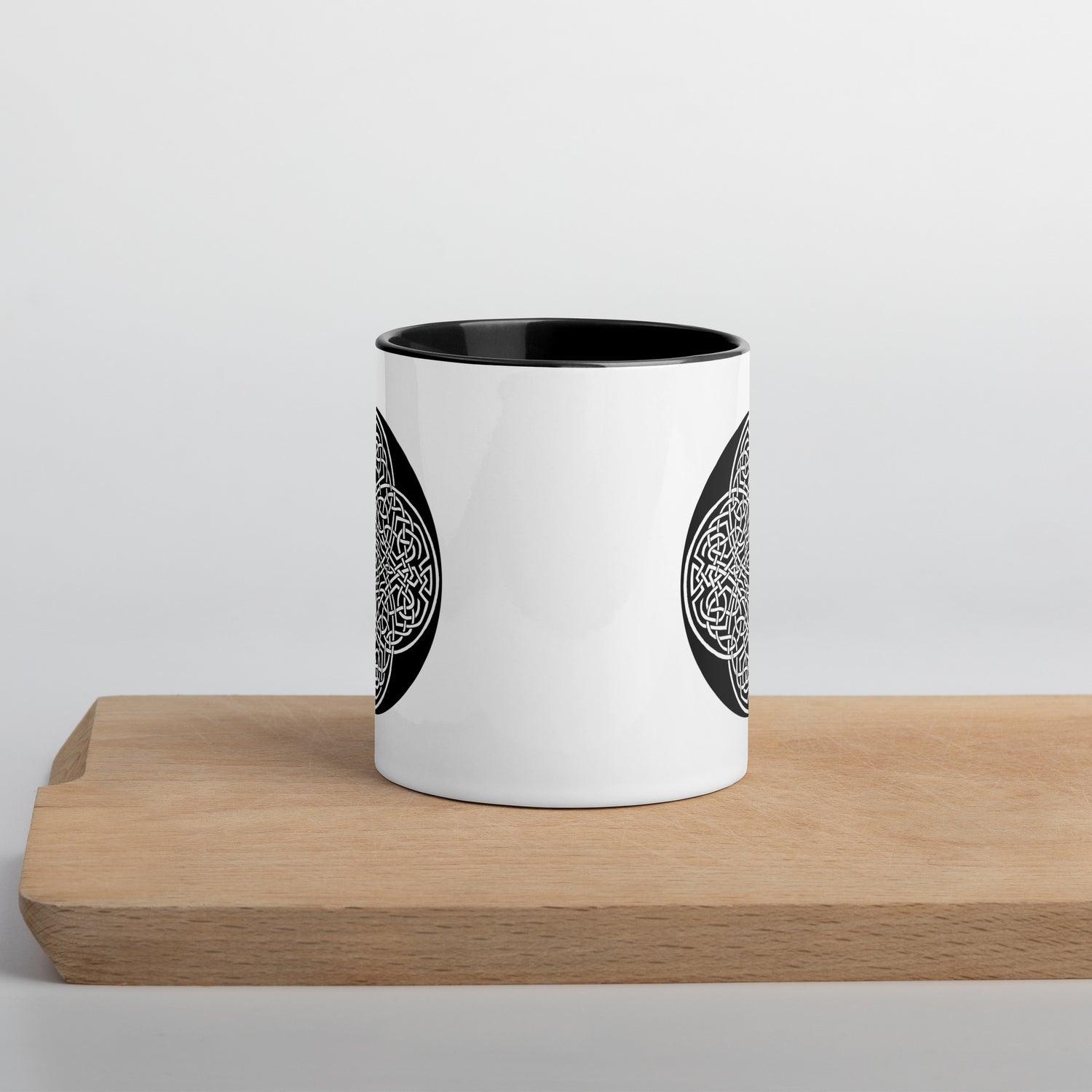 A Xigfireon white ceramic 11oz mug featuring the Black & White Circle iteration of the `Reach Of The Spirit` Celtic knot design, with black handle and inside. This Celtic knot symbolizes Mother Earth.