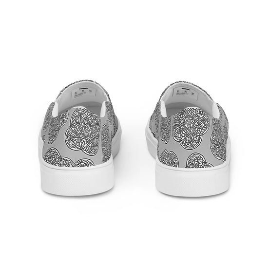 The back side of a pair of Xigfireon canvas slip-ons featuring the Inverted Black & White Solid iteration of the `Reach of The Spirit` Celtic knot pattern.