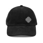 The front side of a black Xigfireon vintage corduroy cap embroidered with the Black & White Solid iteration of the `Reach Of The Spirit` Celtic knot design offset to the left.