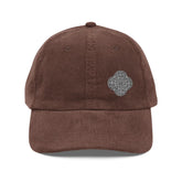 The front side of a brown Xigfireon vintage corduroy cap embroidered with the Black & White Solid iteration of the `Reach Of The Spirit` Celtic knot design offset to the left.