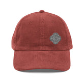 The front side of a burgundy Xigfireon vintage corduroy cap embroidered with the Black & White Solid iteration of the `Reach Of The Spirit` Celtic knot design offset to the left.