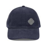 The front side of a navy blue Xigfireon vintage corduroy cap embroidered with the Black & White Solid iteration of the `Reach Of The Spirit` Celtic knot design offset to the left.