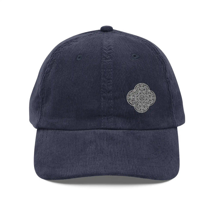 The front side of a navy blue Xigfireon vintage corduroy cap embroidered with the Black & White Solid iteration of the `Reach Of The Spirit` Celtic knot design offset to the left.