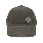 The front side of an olive green Xigfireon vintage corduroy cap embroidered with the Black & White Solid iteration of the `Reach Of The Spirit` Celtic knot design offset to the left.