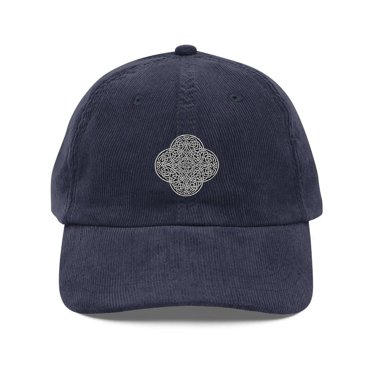 The front side of a navy blue Xigfireon vintage corduroy cap embroidered with the Black & White Solid iteration of the `Reach Of The Spirit` Celtic knot design.