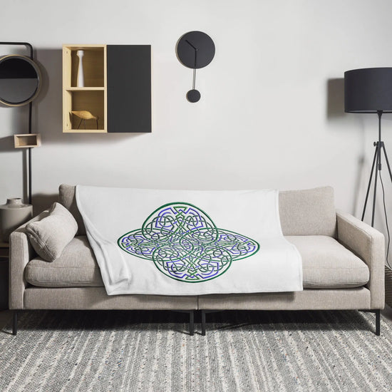 A sofa covered by a 50 inch by 60 inch Xigfireon throw blanket featuring the original Living Colour iteration of the `Reach Of The Spirit` Celtic knot design. The `Reach Of The Spirit` Celtic knot represents the Earth.