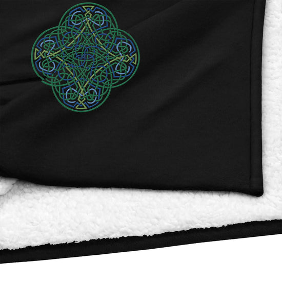 A close-up view of a black Xigfireon sherpa blanket embroidered with the Living Colour iteration of the `Reach Of The Spirit` Celtic knot design.