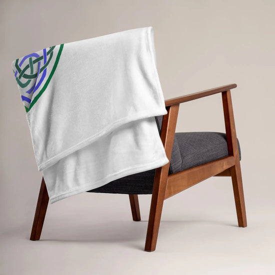 A chair covered by a 50 inch by 60 inch Xigfireon throw blanket featuring the Living Colour Flat iteration of the `Reach Of The Spirit` Celtic knot design. The `Reach Of The Spirit` Celtic knot represents the Earth.