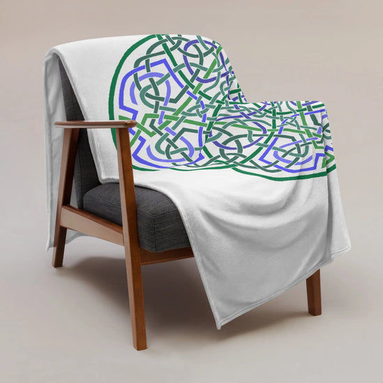 A chair covered by a 60 inch by 80 inch Xigfireon throw blanket featuring the Living Colour Flat iteration of the `Reach Of The Spirit` Celtic knot design. The `Reach Of The Spirit` Celtic knot represents the Earth.