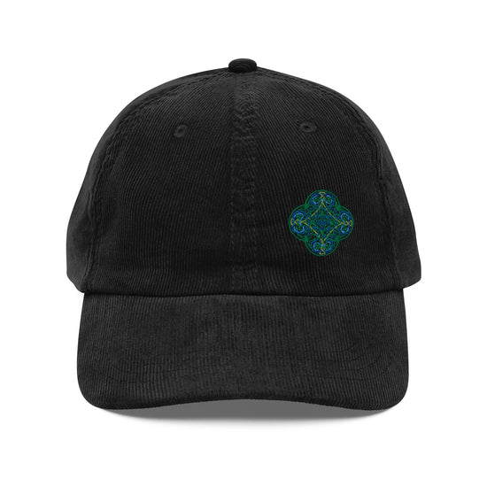 The front side of a black Xigfireon vintage corduroy cap embroidered with the Living Colour iteration of the `Reach Of The Spirit` Celtic knot design offset to the left.