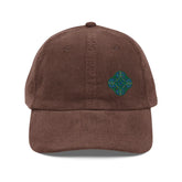 The front side of a brown Xigfireon vintage corduroy cap embroidered with the Living Colour iteration of the `Reach Of The Spirit` Celtic knot design offset to the left.