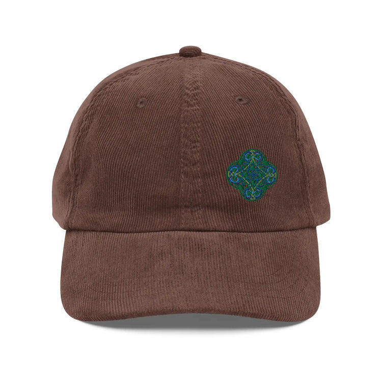 The front side of a brown Xigfireon vintage corduroy cap embroidered with the Living Colour iteration of the `Reach Of The Spirit` Celtic knot design offset to the left.