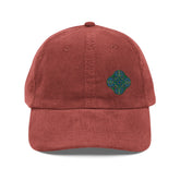 The front side of a burgundy Xigfireon vintage corduroy cap embroidered with the Living Colour iteration of the `Reach Of The Spirit` Celtic knot design offset to the left.