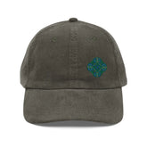 The front side of an olive green Xigfireon vintage corduroy cap embroidered with the Living Colour iteration of the `Reach Of The Spirit` Celtic knot design offset to the left.