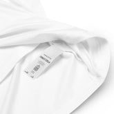 A close-up view of a product tag on a white Xigfireon graphic organic cotton t-shirt featuring the Living Colour iteration of the `Reach Of The Spirit` Celtic knot design. The `Reach Of The Spirit` Celtic knot represents our amazing Mother Earth.