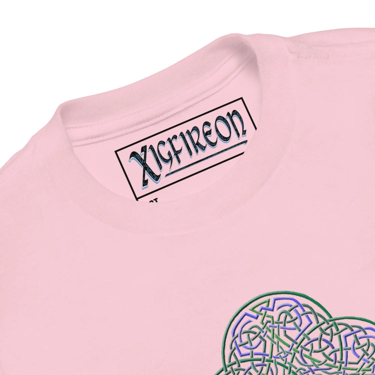 A close-up view of the logo and design on a pink Xigfireon toddler graphic t-shirt featuring the Living Colour iteration of the `Reach Of The Spirit` Celtic knot design. The `Reach Of The Spirit` Celtic knot represents Mother Earth.