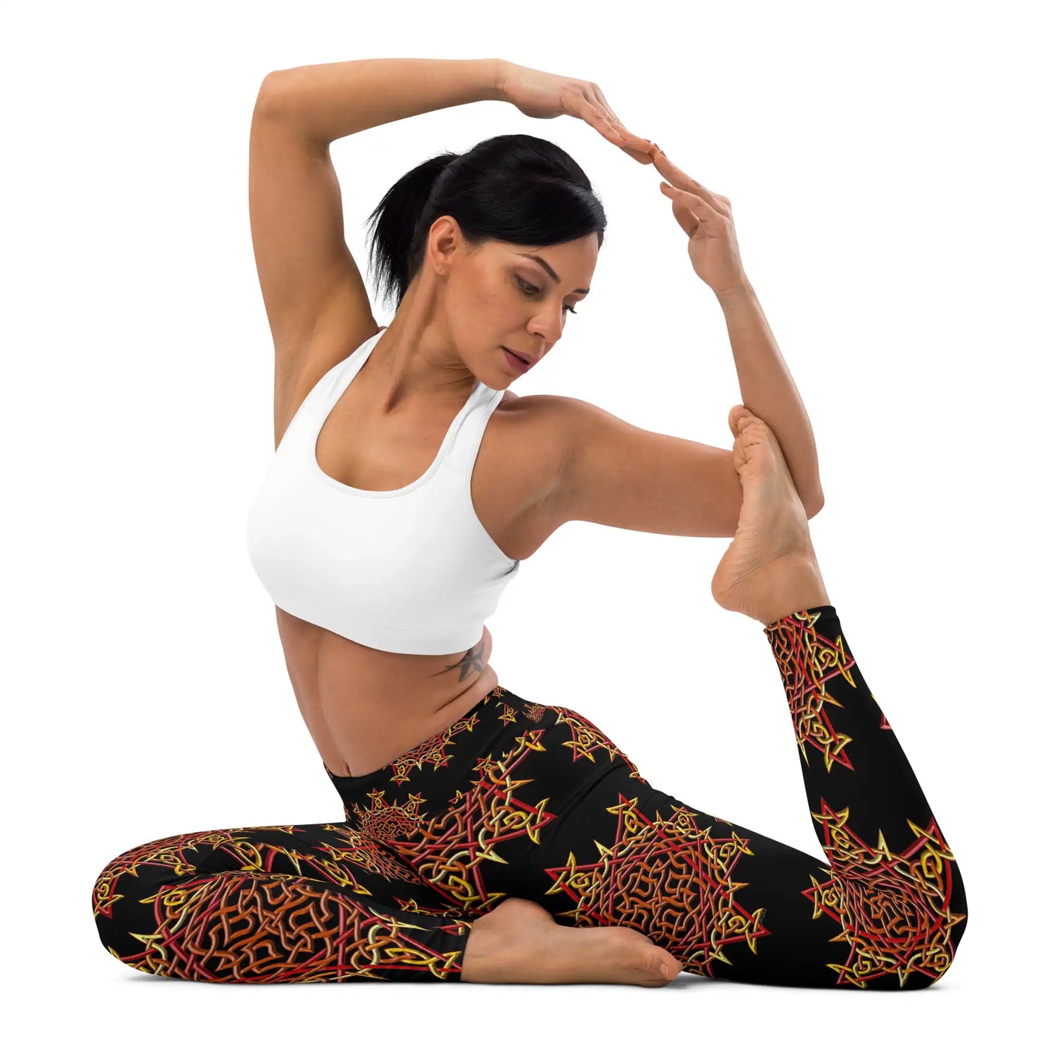 A young in a yoga stance wearing a pair of Xigfireon graphic yoga leggings featuring the Fire Colour Black patterned series of the Morning Star Fire Celtic knot design.