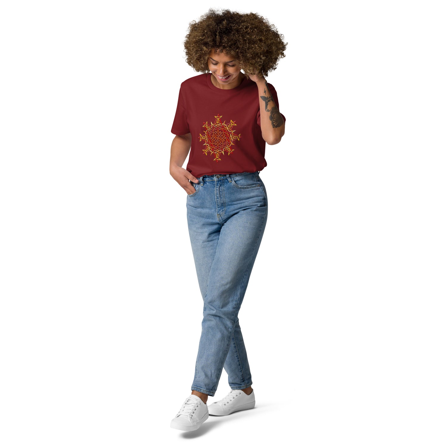 A young woman wearing a burgundy Xigfireon graphic organic cotton t-shirt featuring the Fire Colour iteration of the `Morning Star Fire` Celtic knot design. The `Morning Star Fire` Celtic knot represents our benevolent Father Sun.