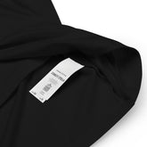 A close-up view of a product tag on a black Xigfireon graphic organic cotton t-shirt featuring the Deep Forest iteration of the `Reach Of The Spirit` Celtic knot design. The `Reach Of The Spirit` Celtic knot represents the glorious Earth.